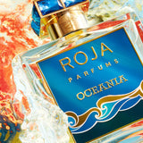 Roja Parfums Oceania – Extrait de Parfum (100ml) bottle surrounded by splashing water and vibrant colors, evoking a fresh oceanic vibe.